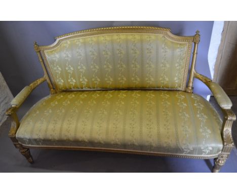 A 19th Century French Gilded Salon Sofa, the upholstered back flanked by reeded uprights above a stuff over seat with carved 