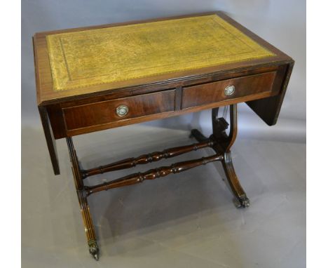 A Reproduction Mahogany Sofa Table, the tooled leather inset top above two frieze drawers raised upon shaped end supports wit