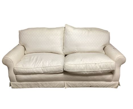 A cream two seater sofa, as found