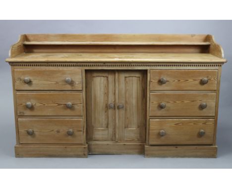 A Victorian pitch-pine inverted break-front dresser base fitted with an open shelf to the low-stage panel back, fitted three 