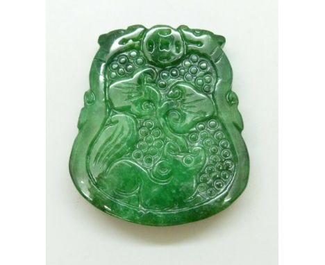 A Chinese carved green stone pendant depicting mythical beasts, tests as jade or jadeite, 4.8cm, 51g