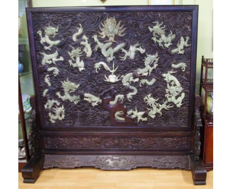 Important large early Chinese hardwood screen with finely carved design and dragon ends, the panel featuring numerous carved 