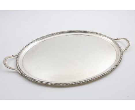 AN EDWARDIAN TWO-HANDLED OVAL TEA TRAY with a gadrooned border, by D &amp; J. Welby, London 1906;  22"  (56 cms) long;  54.5 