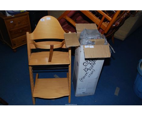A travel cot (boxed) and a wooden feeding chair.