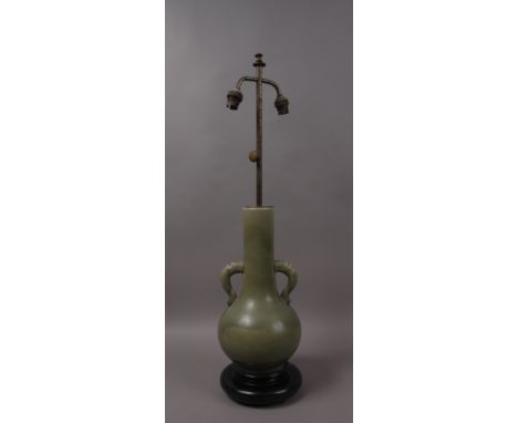 A 20TH CENTURY CHINESE CELADON GLAZED LAMP BASE, with double mask handles, wood base and cream fabric shade, 42cm high