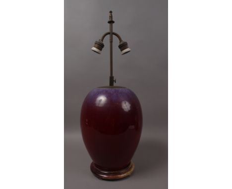 A 20TH CENTURY CHINESE SANG DE BOEUF OVOID LAMP BASE, with wooden base and cream fabric shade, 35cm high