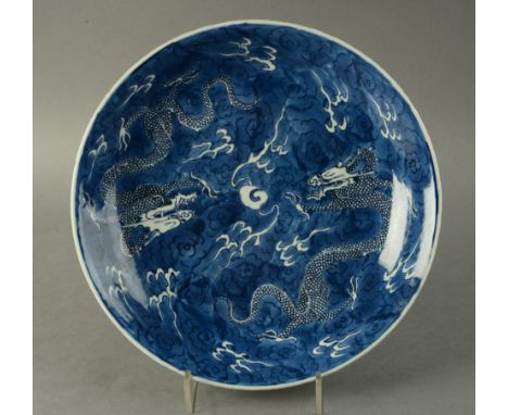 AN 18TH CENTURY CHINESE SAUCER DISH decorated with two dragons chasing a flaming pearl amongst cloud scrolls, 34.5cm diameter