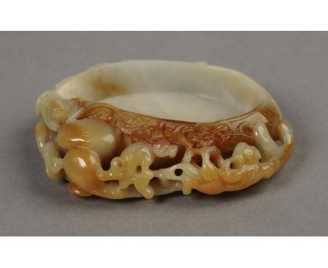 A CHINESE GREEN AND RUST JADE PEBBLE BRUSH WASHER, carved with gourd and monkeys on lotus branches, 8cm wide. See illustratio