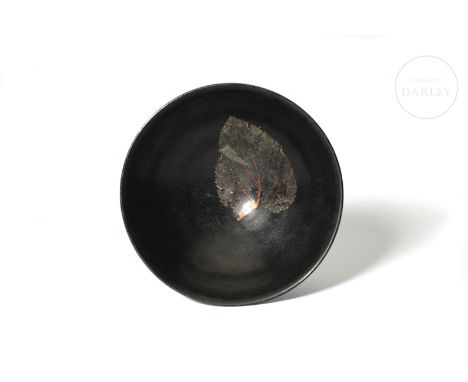 This ceramic is modelled and covered with an intense black glaze, which is more subtle on the rim. It has a small circular ba