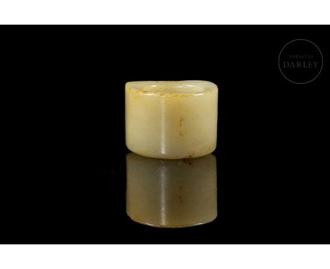 Light-coloured jade, with reddish flecks, carved in the form of a ring, with a rectangular front decorated with reliefs. It s