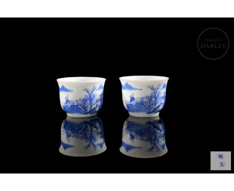 Two small porcelain cups, decorated with underglaze blue enamel. They have a short foot and a curved body, flaring at the mou