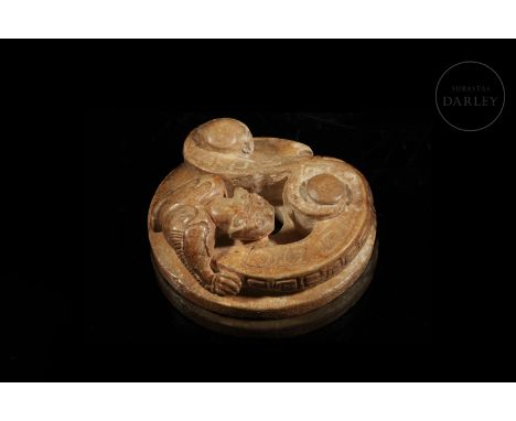 A carved jade disc, copper-coloured with ochre flecks. The surface shows the image of an archaic-style mythical beast with a 