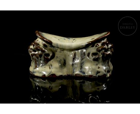 Traditional pillow made of modelled ceramic. It is kidney-shaped, with rounded edges and a slightly curved surface. The body 