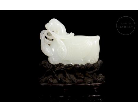 Carved white jade, in one piece. It depicts a beautiful mandarin duck, with wings folded and head raised, holding a lotus bra
