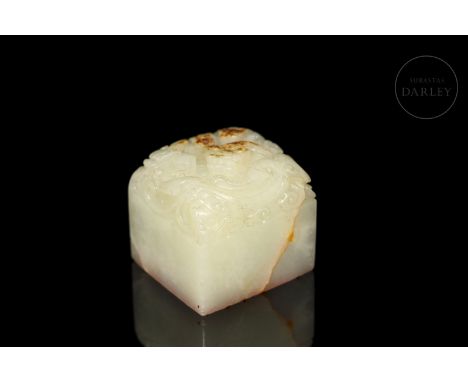 Light jade stamp with reddish stains. It has a square base with incised characters. The upper part shows, in bas-relief, the 