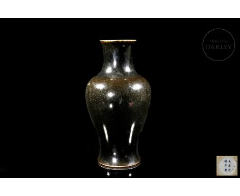 A porcelain vase with a circular base and a balustraded profile, widening at the shoulders, above which is a stylized cylindr