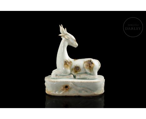 Modelled ceramic in the form of a beautiful stag lying on its bent legs, with its head erect, turned towards the back and cro