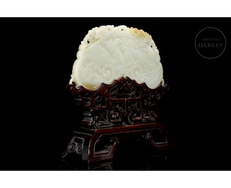 A carved white jade plaque with light amber-toned flecks. Slightly arched in shape, it is adorned with a continuous scene of 