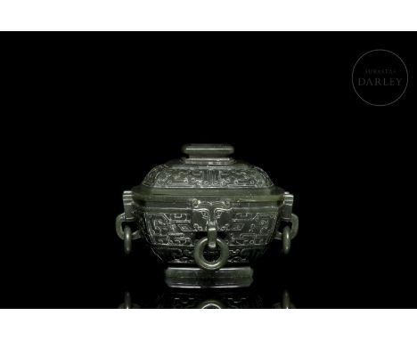 A carved jade ‘?’ vessel of a deep spinach-green colour. It has a quadrangular base, with a narrow stepped and subtly flared 