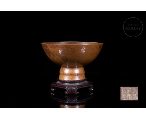 A small ceramic goblet with a tall circular foot on which the deep, curved body rests. It is decorated with a distinctive bro