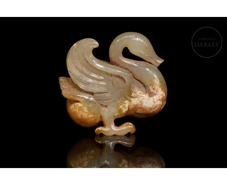 A carved jade of ochre-coloured jade with reddish and light patches. It shows the figure of a bird, standing on its two outst
