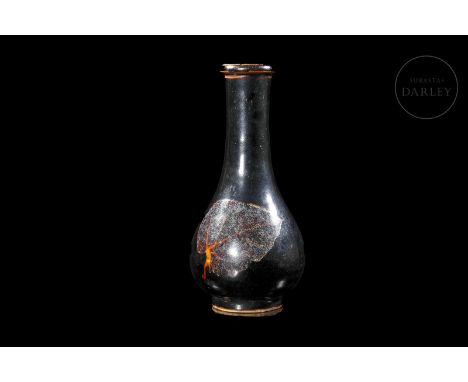 Modelled ceramic covered with a deep black glaze. It has a rounded belly that tapers towards a long cylindrical neck ending i