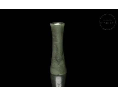 Greenish jade pendant, with slight dark spots. It has a tubular shape, perforated in the centre, with both ends slightly flar