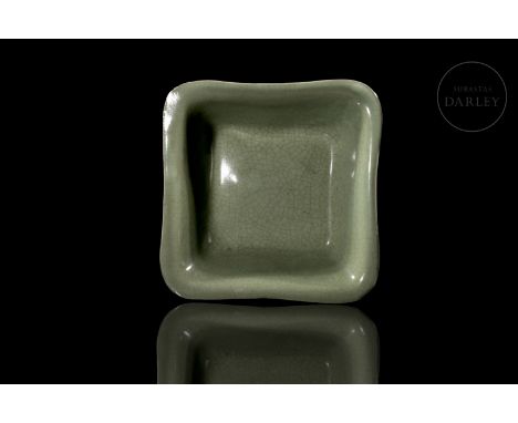 A quadrangular, modelled ceramic vessel with rounded edges and a wide, rounded mouth. It is decorated with a thick olive-gree
