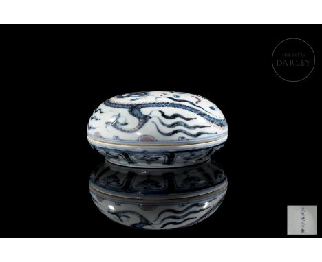 A porcelain box of circular shape, with a concave lid and rounded profile. The exterior is decorated with an imposing three-c