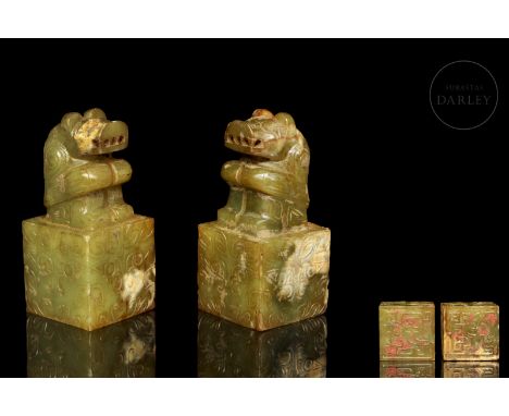 Two greenish carved jade seals with ochre and reddish stains cover the surface. They have a square rectangular base decorated