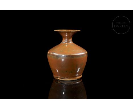 Ceramic modelled in the form of a vase, with a circular base and rounded profile, which widens at the shoulders and narrows i