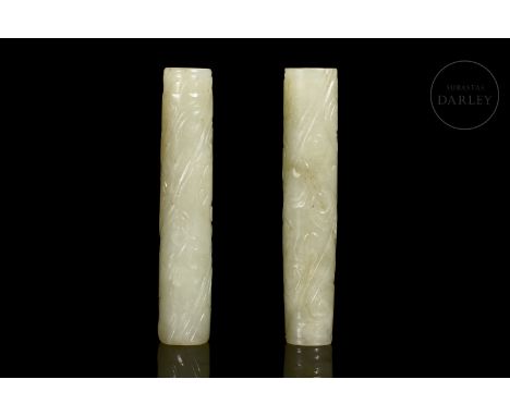 Light-coloured jade, carved in the form of narrow, elongated pendants with a tubular body, pierced by a central hole. The ext