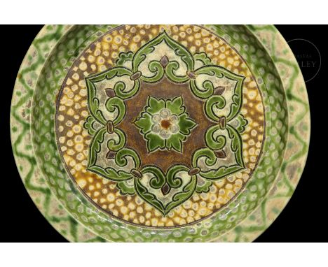 A modelled ceramic dish, with a flat base and wide rim. Decorated with a large central flower, and a beautiful ‘sancai’ (??) 