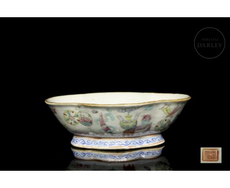 A deep, enamelled porcelain vessel. It has a lobed elliptical shape, standing on a short foot of the same shape. It is decora