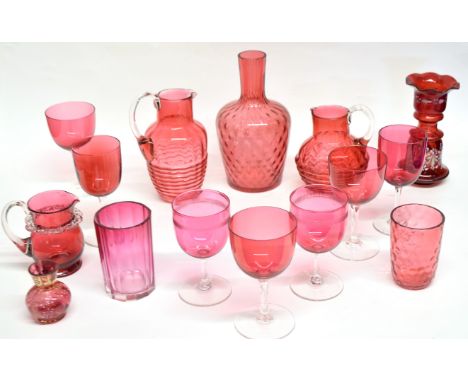 Collection of cranberry glass wares including six wine glasses of various sizes, two jugs, small jug, vase with white leaf de