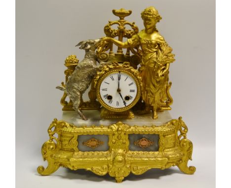 A French gilt metal figural mantel clock featuring a lady hand feeding a silvered goat, enamelled dial, Roman numeral.