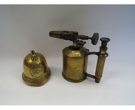 A brass money box as a firemans helmet and a brass blow lamp 