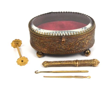 A late 19th Century continental gilt brass oval box on four ball feet the lid with glass bevel panel, containing a silver gil