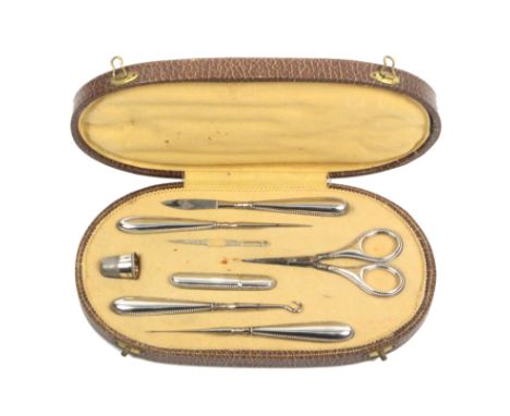 An early 20th Century continental sewing companion, the oval case covered in brown paper to simulate leather, the yellow silk