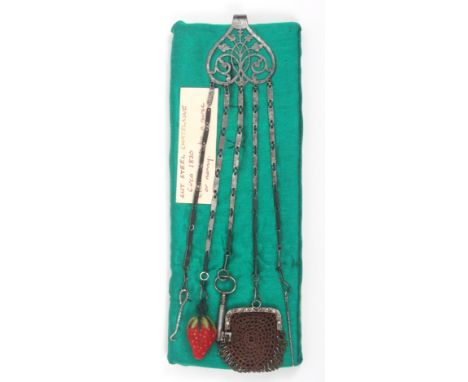 A mid-19th Century steel chatelaine the floral pierced clip with five ribbed link chains to a button hook, a velvet strawberr