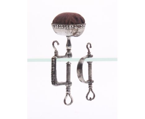 Two steel sewing clamps comprising a cut steel example the rectangular decorated frame below a hook and trough form pin cushi
