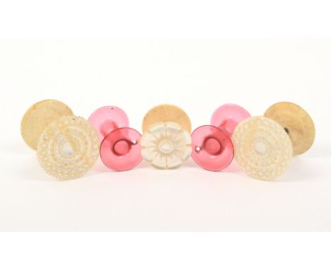 Five reels comprising a rare pair of red glass reels, each with pierced hole to one end, 3cm, a pair of mother of pearl top r