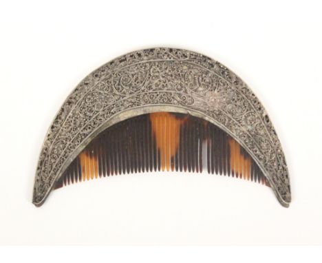An 18th Century tortoiseshell comb in silver filigree frame, the 'D' shaped comb lacking one tooth, the silver frame decorate