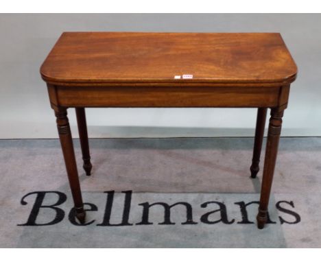 A Victorian mahogany foldover tea table on ring turned supports, 91cm wide x 74cm high.