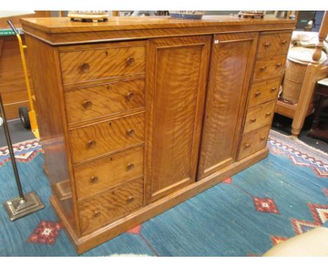 A Victorian satinwalnut dwarf cupboard, with two banks of drawers flanking two cupboard doors  
