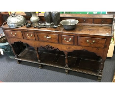 A George III elm dresser base, with faux drawers to superstructure, on turned supports with pot board shelf below, on reeded 