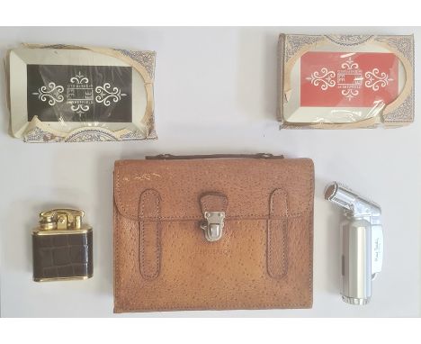 A pigskin card case, enclosing two packs of cards, inscribed 'Henderson', a Pierre Cardin lighter and another lighter (3)&nbs