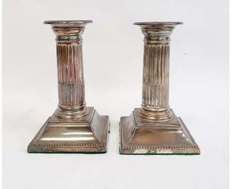 Pair of late 19th/early 20th century silver-mounted candlestick holders with beaded rims to fluted columns, on stepped square