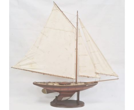 Varnished wood model yacht with canvas sails and metal fittings and the associated wooden stand, 91cm high