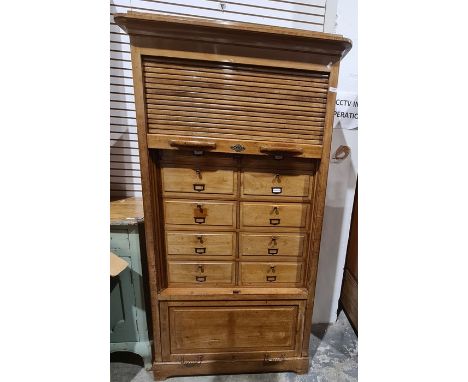 Early 20th century tambour-fronted filing cabinet, the moulded cornice above the tambour front, enclosing 12 fall cupboard do